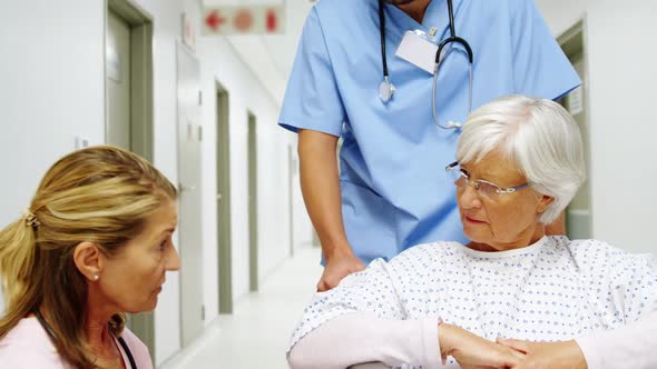 Female doctor interacting with senior patient in the corridor