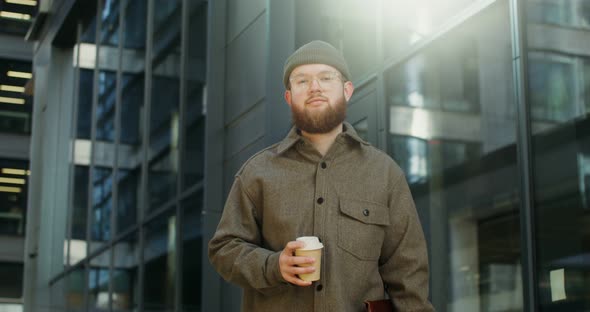 A Bearded Man Standing in the Courtyard of Office Center and Looking at Camera