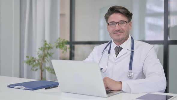 Doctor with Laptop Showing Thumbs Up in Clinic