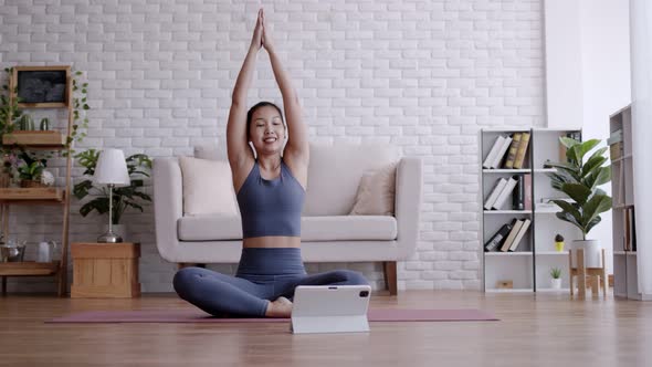 Asian woman look laptop practice yoga lotus pose to meditation online course at home