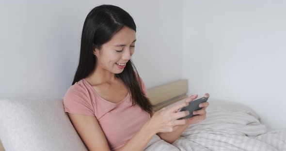 Woman looking at mobile phone on bed