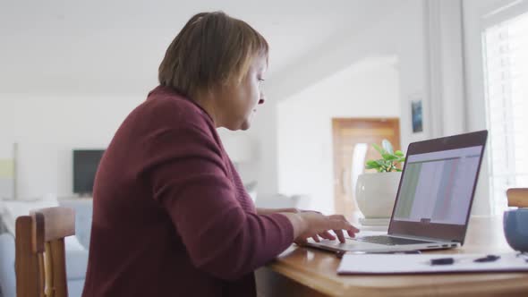 African american senior woman sitting at dining table using laptop