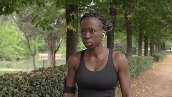 Confident beautiful young athlete walking in the park.Sport,training-slow motion