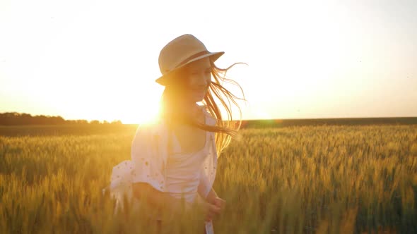 Pretty Child in the Hat Is Running Across the Wheat Field