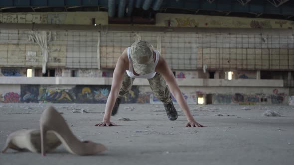 Strong Young Woman in Military Uniform Wringing Herself From the Floor on a Concrete Floor