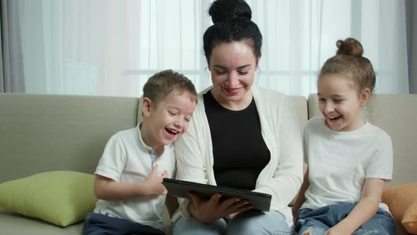 Mother Playing with Child at Home Relaxing Use a Smartphone Cuddling Sit on Sofa DaughterWatch Funny