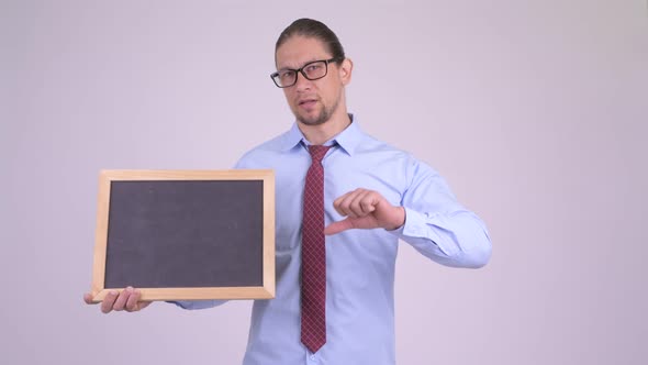 Stressed Businessman Holding Blackboard and Giving Thumbs Down