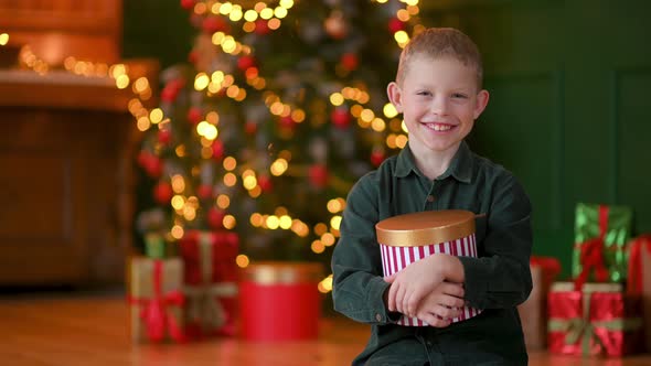 portrait of Happy boy with a gift in her hands sits in a cozy room