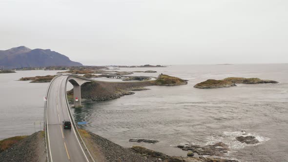 Vehicle Driving On Atlantic Ocean Road Towards Storseisundet Bridge In Norway. - aerial