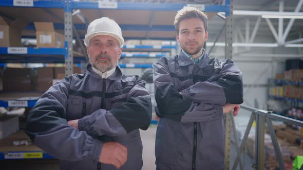 Two Confident Professional Warehouse Workers Crossing Hands Smiling Looking at Camera