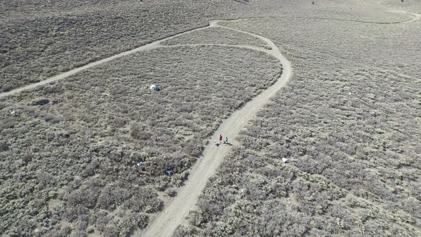 Aerial shot of a young man and woman trail running with dog on scenic mountain trail.