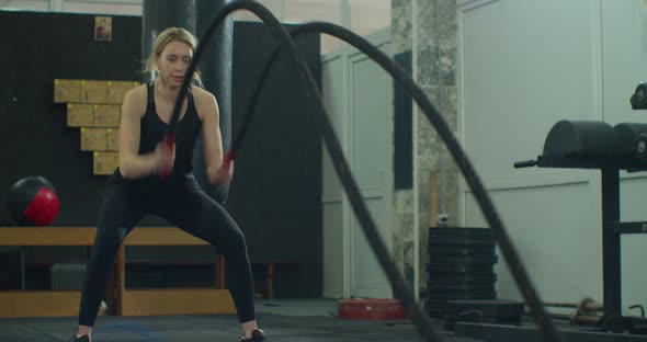 Fit Female Athlete Moving a Rope in Wave Motion As Part of Fitness Regime