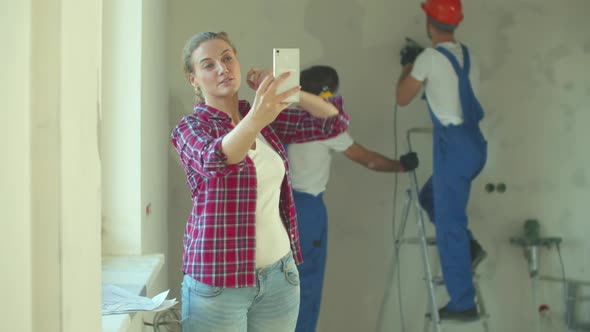 Happy Woman Makes a Photo, Builders Work at the Background