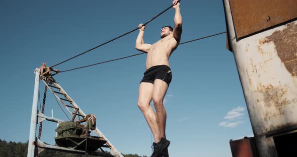 Young Male Athlete Sportsman Training Doing Pull Ups at a Horizontal Bar. Workout Outdooor at Summer