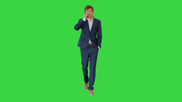 Handsome Young Businessman Talking on the Phone While Walking on a Green Screen, Chroma Key.