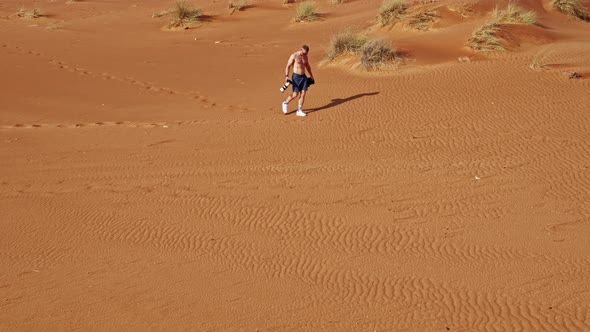 Shirtless Man Walking Through Desert In Dubai