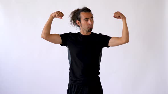 Long Haired Hispanic Man with Goatee Performs Active Wrist Stretch in Front of White Studio Backdrop