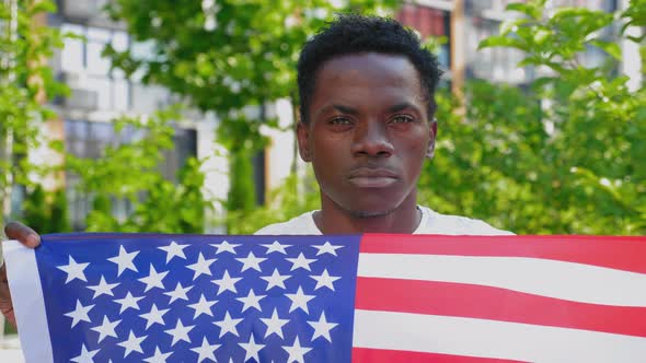 Close Up Smiling Afroamerican Man Holding American Flag Looks Camera in Summer