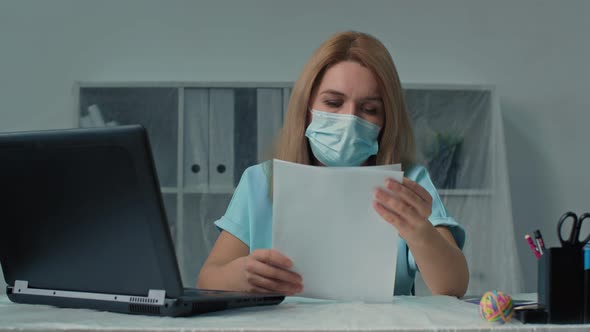 Woman in Protective Mask Working with Documents and Laptop in Modern Office