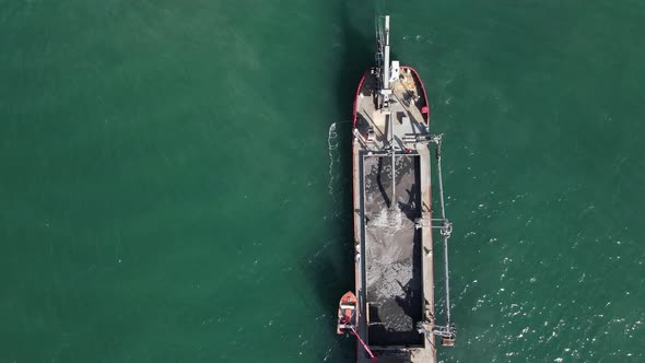 Unique close-up view of large industrial dredging vessel pumping tons of sand into the ships storage