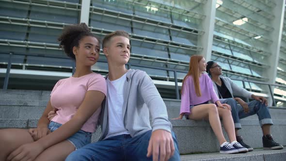 Two Multiracial Couple of Teenagers Sitting Stairs Outdoors, Romantic Youth