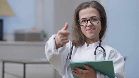 Portrait of Confident Smart Female Doctor in Eyeglasses Gesturing Thumb Up Smiling Looking at Camera