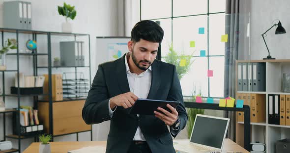 Businessman in Suit Standing in front of Camera and Working on Tablet PC