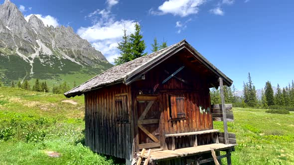 Old Wooden Mountain hiker house in idyllic landscape of Austria during sunlight - Woman hiking for b