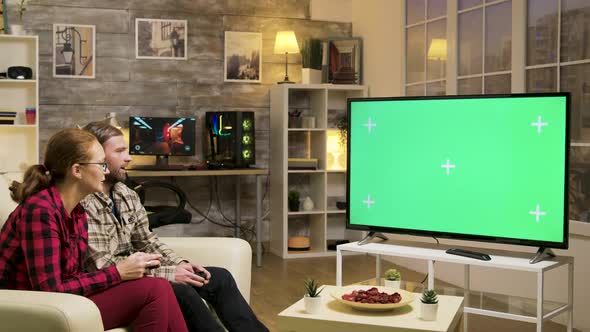 Relaxed Couple Sitting on Sofa Playing Video Games