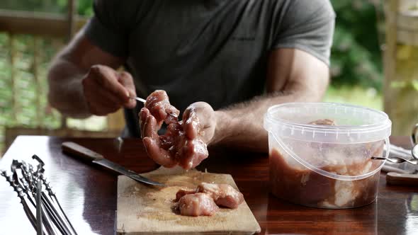 Man is Preparing Meat for Grilling Putting Pieces on Skewers
