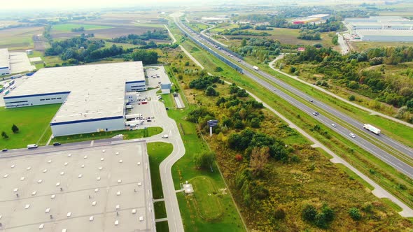 Big logistics terminal in countryside near highway, Delivery center traffic on the highway aerial sh