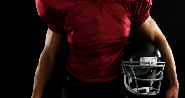 American football player holding a ball and head gear