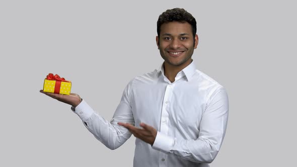 Happy Hindu Man Holding Gift Box and Pointing with Hand