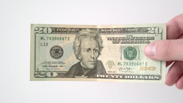 A Hand Shows a 20 Dollar Bill a Man Holds a Banknote on a White Background Closeup