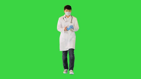 Young Asian Doctor Walks Taking Off Gloves and Mask on a Green Screen Chroma Key