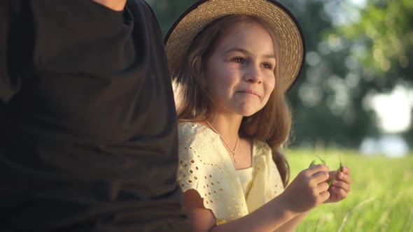 Cute Curios Girl Smiling Talking with Unrecognizable Man Sitting on Green Spring Summer Meadow