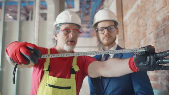 Construction Worker and Architect with Ruler on Site