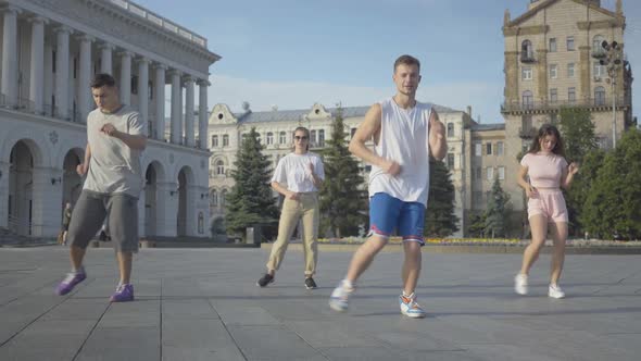 Group of Professional Dancers Performing on City Square at Sunrise, Four Confident Caucasian Men 