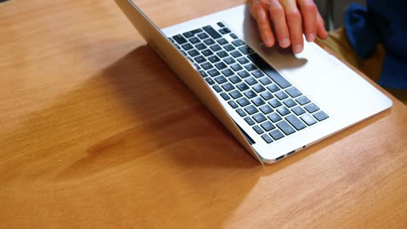 Businessman having cup of coffee while using on laptop