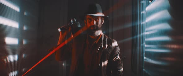 Man wearing hat holding vintage camera in lit flash and laser light