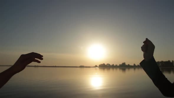 Silhouette of Hands Hold Together at Sunrise