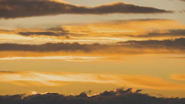 Time lapse footage of fast moving clouds on yellow sky at sunset.