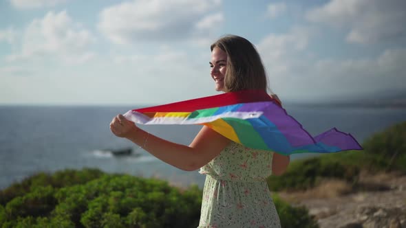 Cheerful Caucasian LGBT Woman with Rainbow Flag Smiling Stretching Hands in Slow Motion Admiring