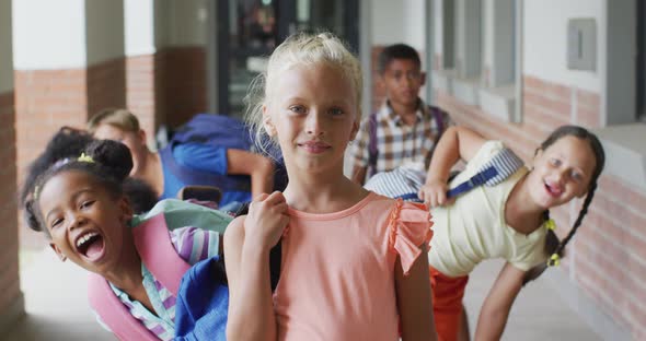 Video of happy caucasian girl and diverse pupils at schoot corridor
