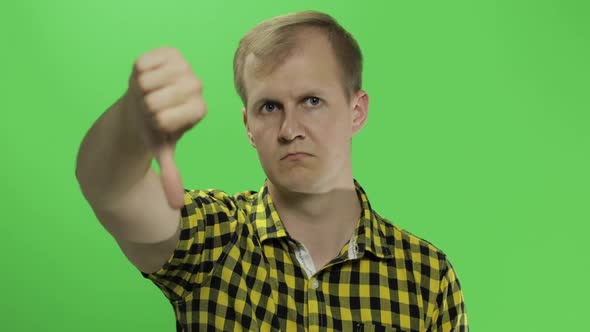 Caucasian Young Man in Yellow Shirt Showing No and Giving His Thumb Down