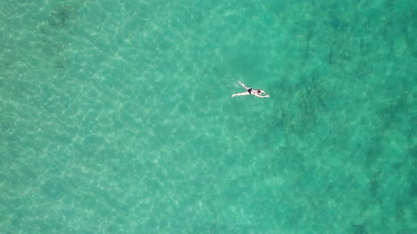 Top Down Aerial View of Woman Swims on Crystal Clear Water in a Transparent Sea