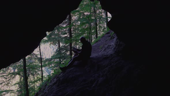 Hiker relax and read books outdoor, in a cool cave