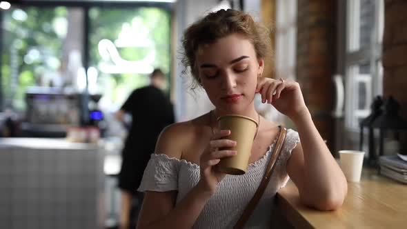 Young Woman Sniff Aroma of Coffee Sitting in a Cafe