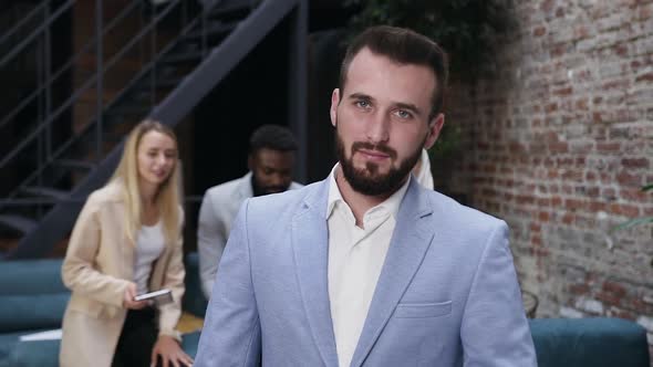 Handsome Serious Bearded Young Businessman in Blue Jacket Looking at Camera