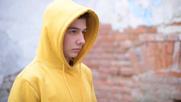 a teenager in a yellow sweatshirt looks in front of him
